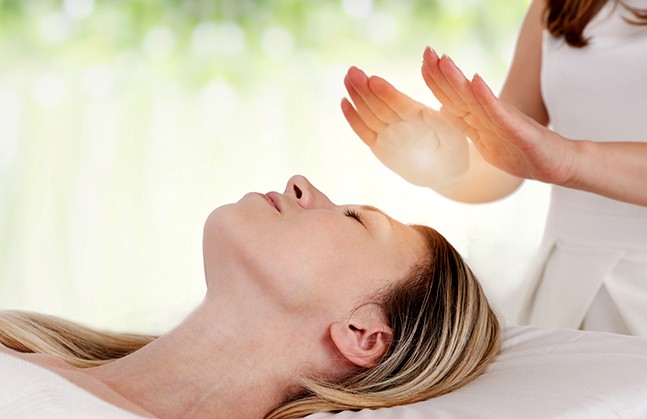 woman performing energy healing on another woman. Hands raised above her head