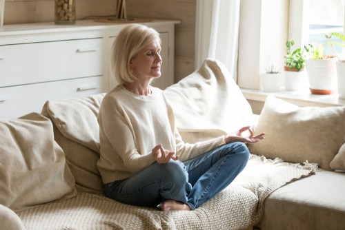 senior woman doing mindful meditation on the couch